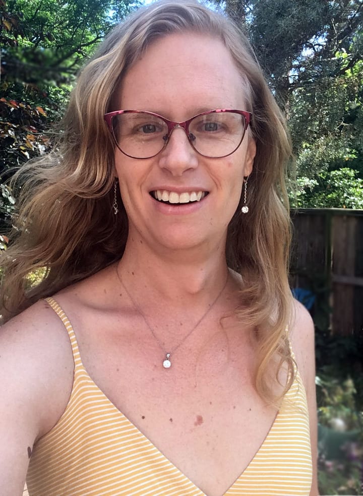 Evelyn wearing a yellow dress with wavy dirty blond hair and matching necklace and earrings with cz diamonds.